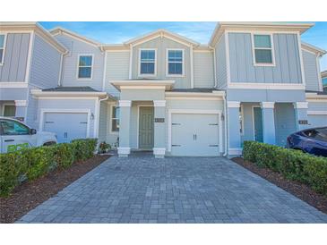 Two-story townhome with gray siding, paver driveway, and landscaping at 4708 Tribute Trl, Kissimmee, FL 34746