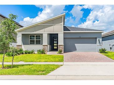 One-story home with gray siding, stone accents, and a two-car garage at 1146 Boardwalk Pl, Kissimmee, FL 34747