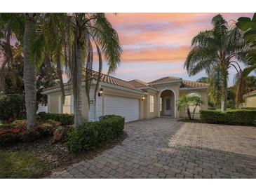 Charming single-story home with a brick driveway, lush landscaping, and a tile roof at sunset at 12161 Obelia Ln, Orlando, FL 32827