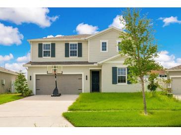 Charming two-story home with a well-manicured lawn and a basketball hoop over the garage at 332 Bow Ln, Haines City, FL 33844