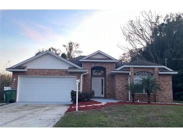 Brick house with a two-car garage and landscaped front yard at 113 W 1St St, Debary, FL 32713