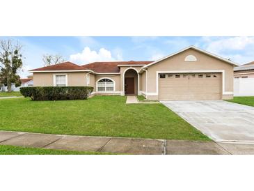 Tan one-story house with a two-car garage and well-maintained lawn at 2543 Sage Dr, Kissimmee, FL 34758