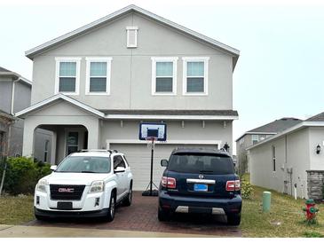 Two-story house with gray siding, two-car driveway, and basketball hoop at 7835 Syracuse Dr, Clermont, FL 34714
