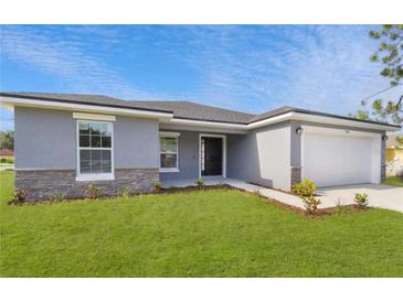 One-story home with gray exterior, stone accents, and a white garage door at 943 Derbyshire Dr, Kissimmee, FL 34758