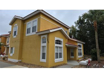 Two-story yellow house with white trim, and a landscaped yard at 1013 Park Ridge Cir, Kissimmee, FL 34746