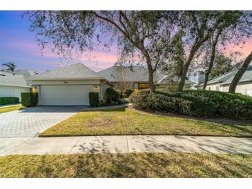 Single-story house with a two-car garage, landscaping, and a brick driveway at 1501 Edgewater Dr, Mount Dora, FL 32757