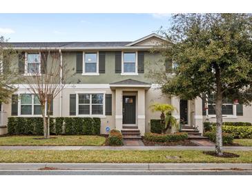 Two-story townhome with green exterior, landscaping, and walkway at 16133 Pebble Bluff Loop, Winter Garden, FL 34787