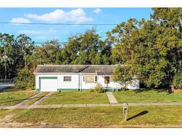 White single-story house with attached garage, driveway, and landscaped lawn at 208 S Main Ave, Minneola, FL 34715