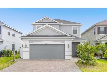 Two-story house with gray siding, a gray three-car garage, and a brick paver driveway at 2438 Pearl Cider Street, Orlando, FL 32824