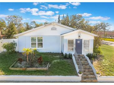 Cute bungalow with a light blue exterior, stone steps, and nicely landscaped yard at 305 S Halifax Dr, Ormond Beach, FL 32176