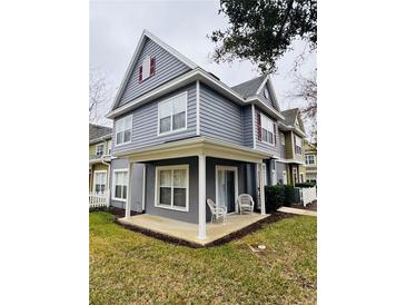 Two-story townhome with gray siding, covered patio, and landscaping at 4563 Yellowgold E Rd # 108, Kissimmee, FL 34746