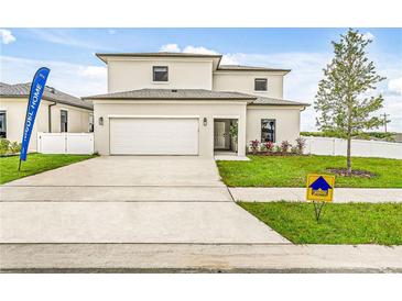 Two-story house with attached garage, landscaping, and driveway at 6230 Chorus Dr, Mascotte, FL 34753