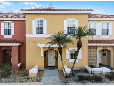 Charming yellow townhome with well-kept landscaping, featuring two palm trees and white accents at 1068 Park Ridge Cir, Kissimmee, FL 34746