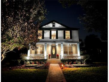 Two-story house with a brick pathway, lush landscaping, and nighttime illumination at 11413 Camden Park Dr, Windermere, FL 34786