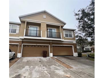 Tan two-story townhome with double garage and small balcony at 1976 Estancia Cir # 1976, Kissimmee, FL 34741