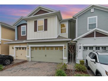 Two-story townhome with a light green garage door and landscaped front yard at 2583 Sedge Grass Way, Orlando, FL 32824