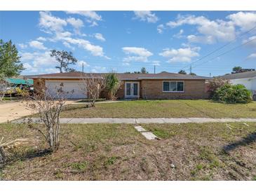 Charming brick home featuring a two-car garage and neatly manicured front lawn at 2825 Greenfield Ave, Orlando, FL 32808