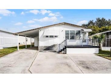 White single-wide mobile home with carport and small deck at 50989 Highway 27 # 25, Davenport, FL 33897