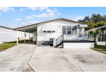 White single-wide manufactured home with carport and small deck at 50989 Highway 27 # 25, Davenport, FL 33897