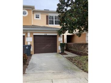 Two-story townhome with brown garage door and landscaping at 538 Bexley Dr, Davenport, FL 33897