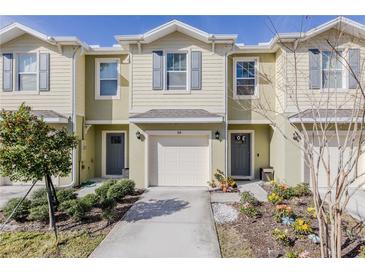 Tan two-story townhome with gray doors, attached garage, and landscaping at 54 Bella Oaks Dr, Port Orange, FL 32129