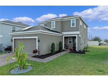 Beautiful two-story home featuring a manicured lawn, brick pathway, and an attached two-car garage at 958 Anna Pl, Davenport, FL 33837