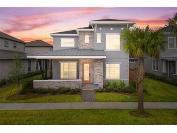 Two-story home with gray siding, stone accents, and a metal roof at 13415 Laxness St, Orlando, FL 32827