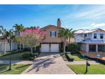 Tan two-story house with two-car garage, landscaping, and a view of neighboring homes under construction at 16324 Vetta Dr, Montverde, FL 34756