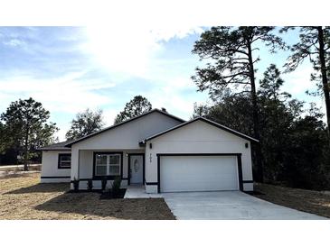 Newly constructed home with white exterior, black accents, and a two-car garage at 702 Marion Oaks Manor, Ocala, FL 34473