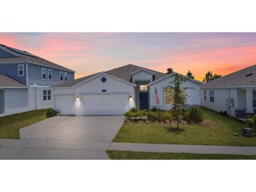 Charming single-story home with a well-manicured lawn, a two car garage, and beautiful sunset at 7149 Dilly Lake Ave, Groveland, FL 34736