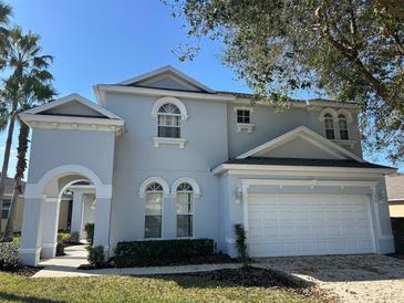 Charming two-story home with landscaped yard, white trim, and an attached two-car garage at 219 Plumoso Loop, Davenport, FL 33897