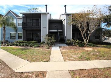 Two-story condo building with gray and blue siding, walkway, and landscaping at 3700 Idlebrook Cir # 208, Casselberry, FL 32707