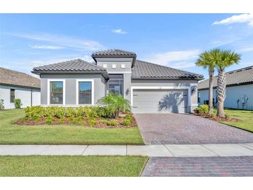 Charming single-story home with a tile roof, paver driveway, well-manicured lawn, and lush landscaping at 1511 Goblet Cove St, Kissimmee, FL 34746