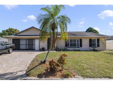 Charming single-story home featuring a well-manicured lawn, brick driveway, and mature palm tree in a sunny setting at 2537 Lanier Rd, Kissimmee, FL 34744