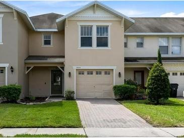 Tan two-story townhome with attached garage and well-manicured lawn at 5454 Caramella Dr, Orlando, FL 32829