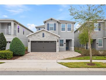 Two-story house with gray siding, stone accents, and a brown garage door at 7783 Westland Dr, Kissimmee, FL 34747