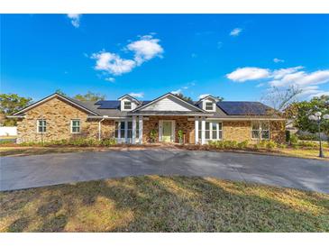 Brick home with solar panels, a large driveway, and well-manicured landscaping at 1203 Waverly Way, Longwood, FL 32750