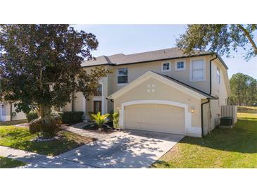 Two-story house with beige exterior, large garage, and landscaping at 13214 Meergate Cir, Orlando, FL 32837