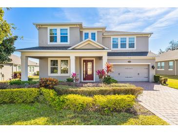 Two-story house with a red door, gray siding, and landscaped yard at 15944 Citrus Knoll Dr, Winter Garden, FL 34787