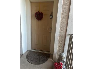 Inviting entryway with a heart-shaped wreath and decorative doormat at 3332 Robert Trent Jones Dr # 30303, Orlando, FL 32835