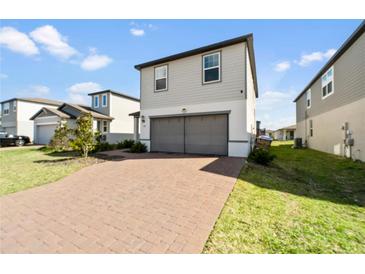 Two-story home with a two-car garage and brick-paved driveway in a modern neighborhood at 581 Sun Warbler Way, St Cloud, FL 34771