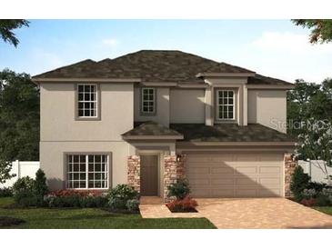 Two-story house with a gray exterior, brick accents, and a two-car garage at 733 Ginger Dr, Haines City, FL 33844