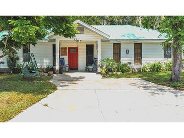 White house with red door, teal roof, and rocking chairs on porch at 750 S Dudley Ave, Bartow, FL 33830