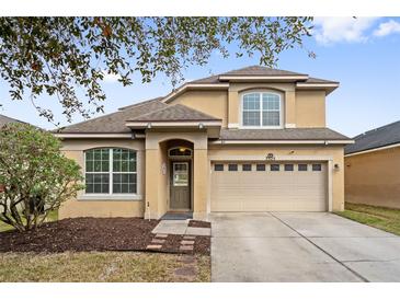 Two-story house with tan exterior, two-car garage, and landscaping at 7525 Azalea Cove Cir, Orlando, FL 32807