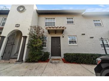 Inviting exterior of a two-story stucco home with a dark brown door and well-manicured landscaping at 805 Weldona Ln # 104, Orlando, FL 32801