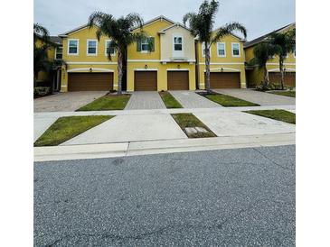 Three-unit townhome building with attached garages and palm trees at 9884 Red Eagle Dr, Orlando, FL 32825