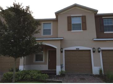 Tan two-story townhome with attached garage and landscaping at 10975 Savannah Landing Cir, Orlando, FL 32832