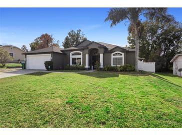 One-story home with gray exterior, attached garage, and lush lawn at 1210 Kenway Ave, Deltona, FL 32738