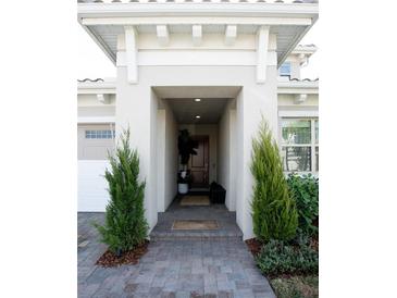 Inviting front entrance with a covered walkway, stone pathway, and lush landscaping at 13586 Abberwick Dr, Orlando, FL 32832