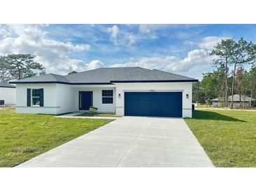 Charming single-story home featuring a blue garage door, and well-manicured lawn at 15122 Sw 61St Court Rd, Ocala, FL 34473